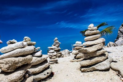 Low angle view of stack of rocks against blue sky