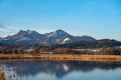 Scenic view of lake and mountains against blue sky