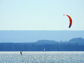 Person paragliding over sea against sky