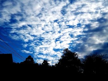 Low angle view of silhouette trees against blue sky