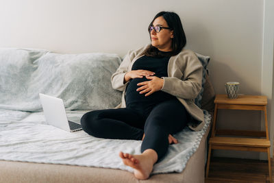 Young woman sitting on sofa at home