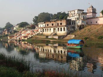 Buildings by lake against sky