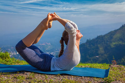Woman doing ashtanga vinyasa yoga asana dhanurasana - bow pose