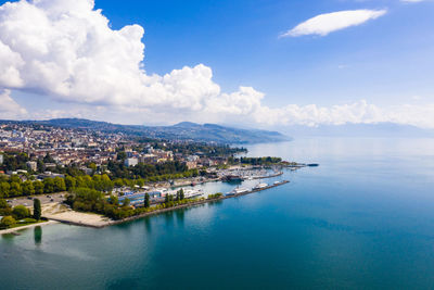 Aerial view of townscape by sea against sky