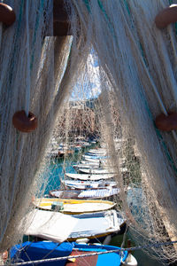 Rowboats seen through commercial fishing net at harbor