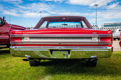 Red vintage car on field against sky