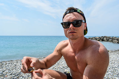 Portrait of young man wearing sunglasses at beach