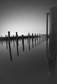 Wooden posts on pier in sea against clear sky