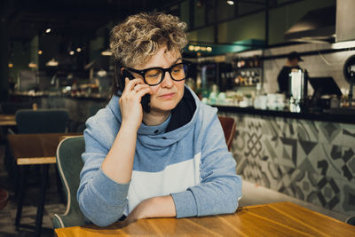 Mature woman with eyeglasses talking on phone in cafe