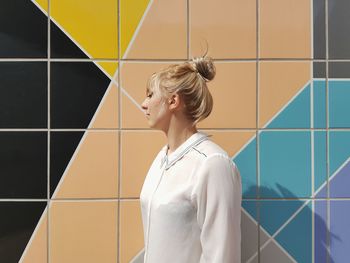 Beautiful woman standing against multi colored tiled wall