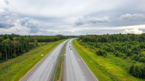 Panoramic shot of road amidst trees on field against sky