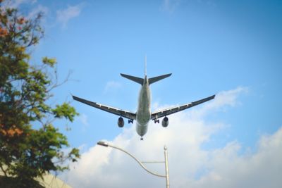 Low angle view of airplane flying against blue sky