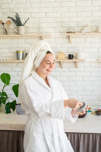 Young woman with arms raised in bathroom