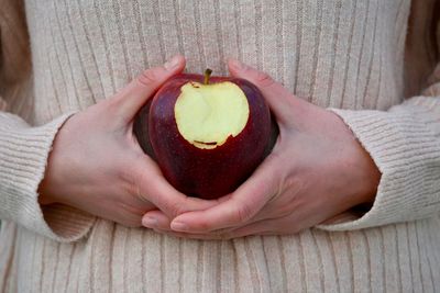 Midsection of woman holding apple