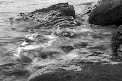Close-up of flowing water on rock at beach