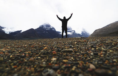 Rear view of person standing on rock against sky