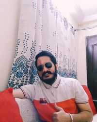 Portrait of young man wearing sunglasses sitting at home