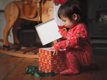 Side view of baby girl holding gift box at home