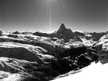 Scenic view of snow covered mountains against blue sky