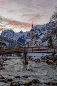 Church by building against sky during winter