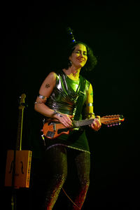 Man playing guitar against black background