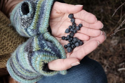 Midsection of woman in knitted gloves holding berries