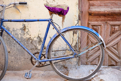Blue bicycle with magenta seat. carved wooden door.