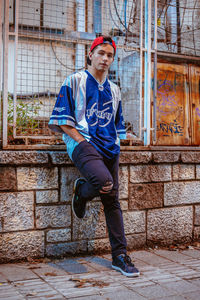 Portrait of young man standing against brick wall