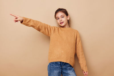 Portrait of young woman standing against pink background