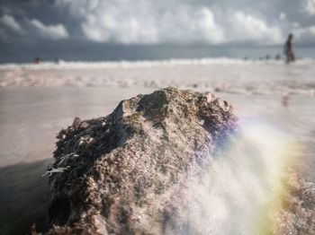 Rock on beach against sky