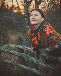 Portrait of young woman standing against trees
