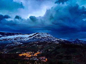 Scenic view of snowcapped mountains against dramatic sky