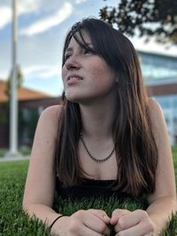 Young woman looking away while lying on grassy field at park