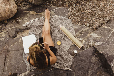 Directly above view of woman using smart phone sitting on rock