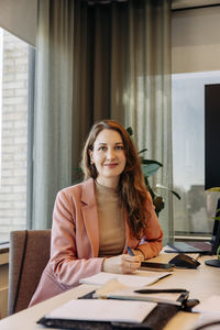 Portrait of smiling businesswoman sitting at desk in coworking office