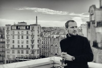 Man with wineglass standing on building terrace
