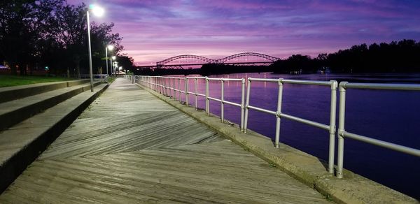 Footbridge over river against sky at night