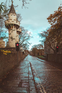 Empty footpath amidst buildings against sky