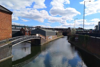 Bridge over river amidst buildings in city against sky