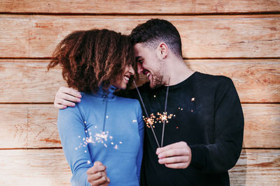 Young couple holding hands standing against wooden wall