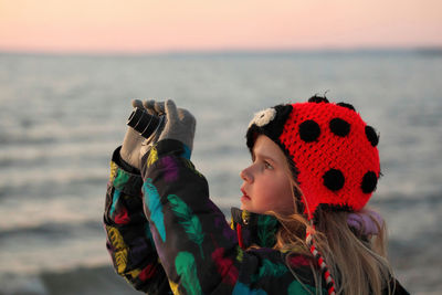 A 9 year old girl practices her photography and camera skills at the beach in the evening