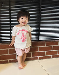 Portrait of cute girl standing against wall