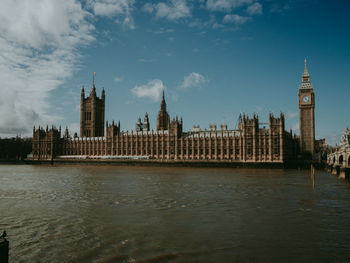 Buildings by river against sky