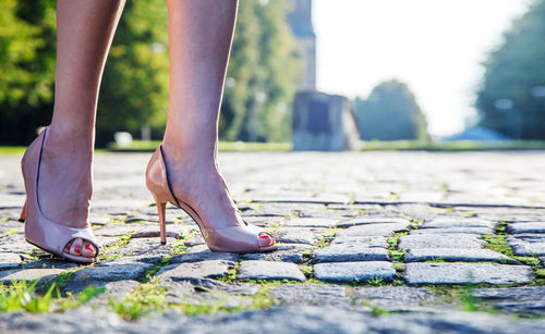 Low section of woman wearing high heels standing on footpath