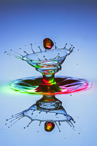 Close-up of water drop in mid-air against blue background