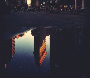 Reflection of building in puddle at night