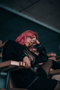 Low angle view of woman with dyed hair sitting on chair
