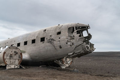 Abandoned airplane on land against sky