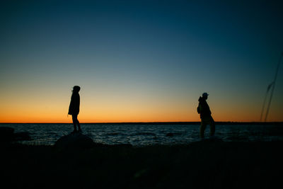 Silhouette man standing on beach against sky during sunset