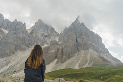 Rear view of woman standing on mountain against sky